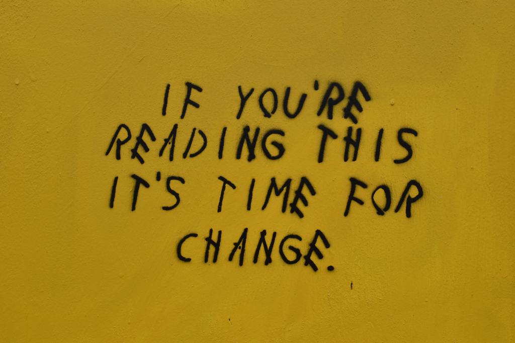A yellow wall on which is spray painted 'if you are reading this it's time for change'
